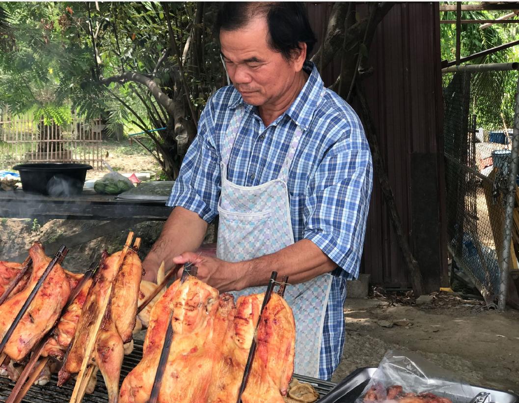A cook preparing grilled chicken at Whale Market