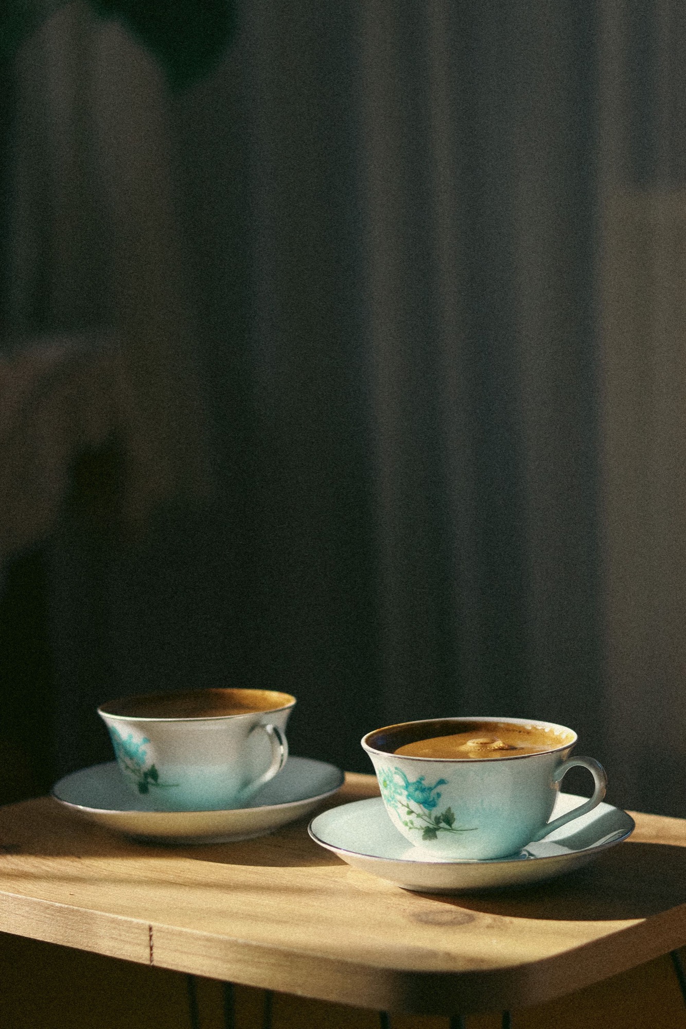 Two porcelain coffee cups on a dark cafe table
