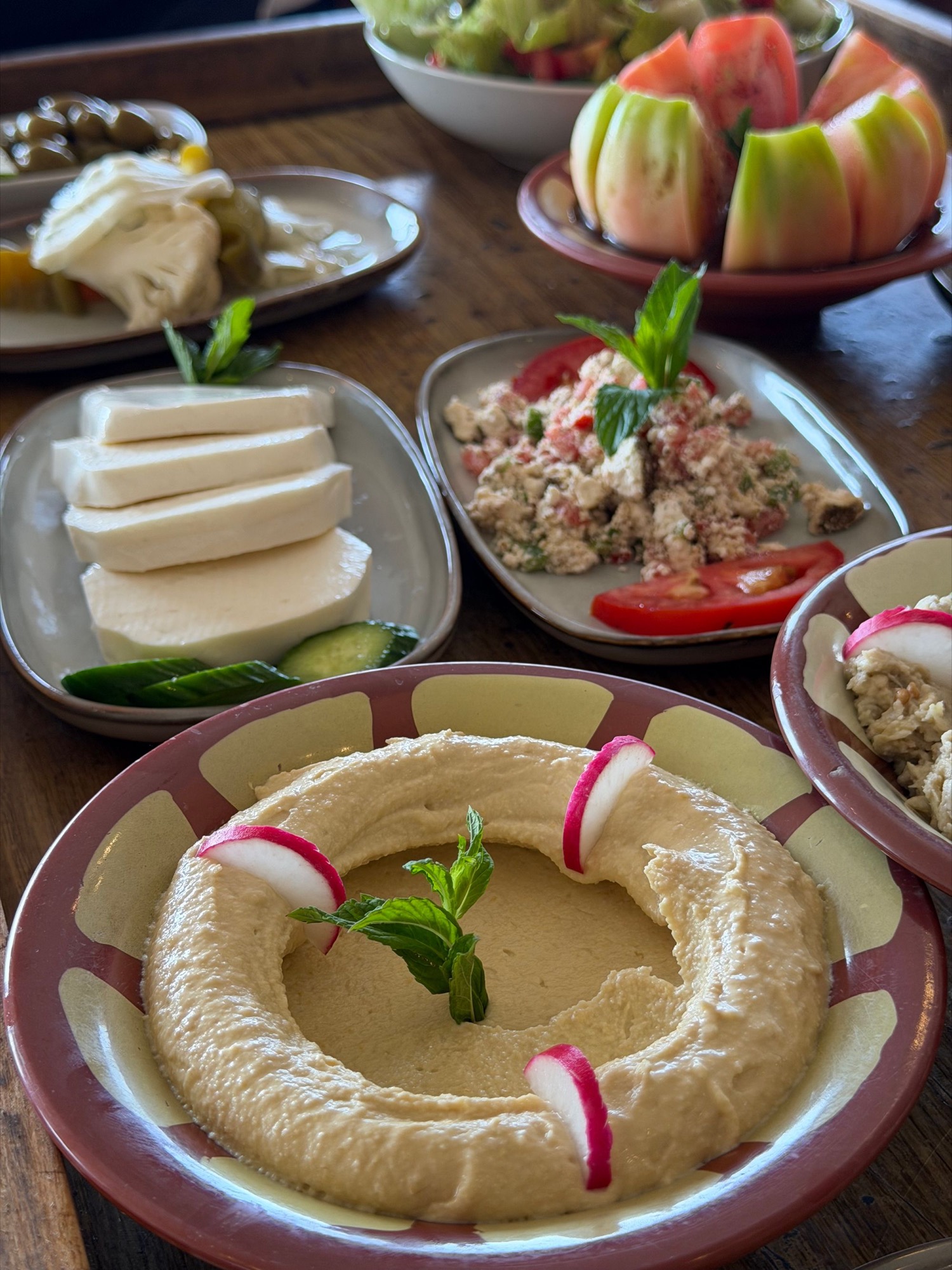 Middle Eastern table with hummus, fresh vegetables and shared dishes