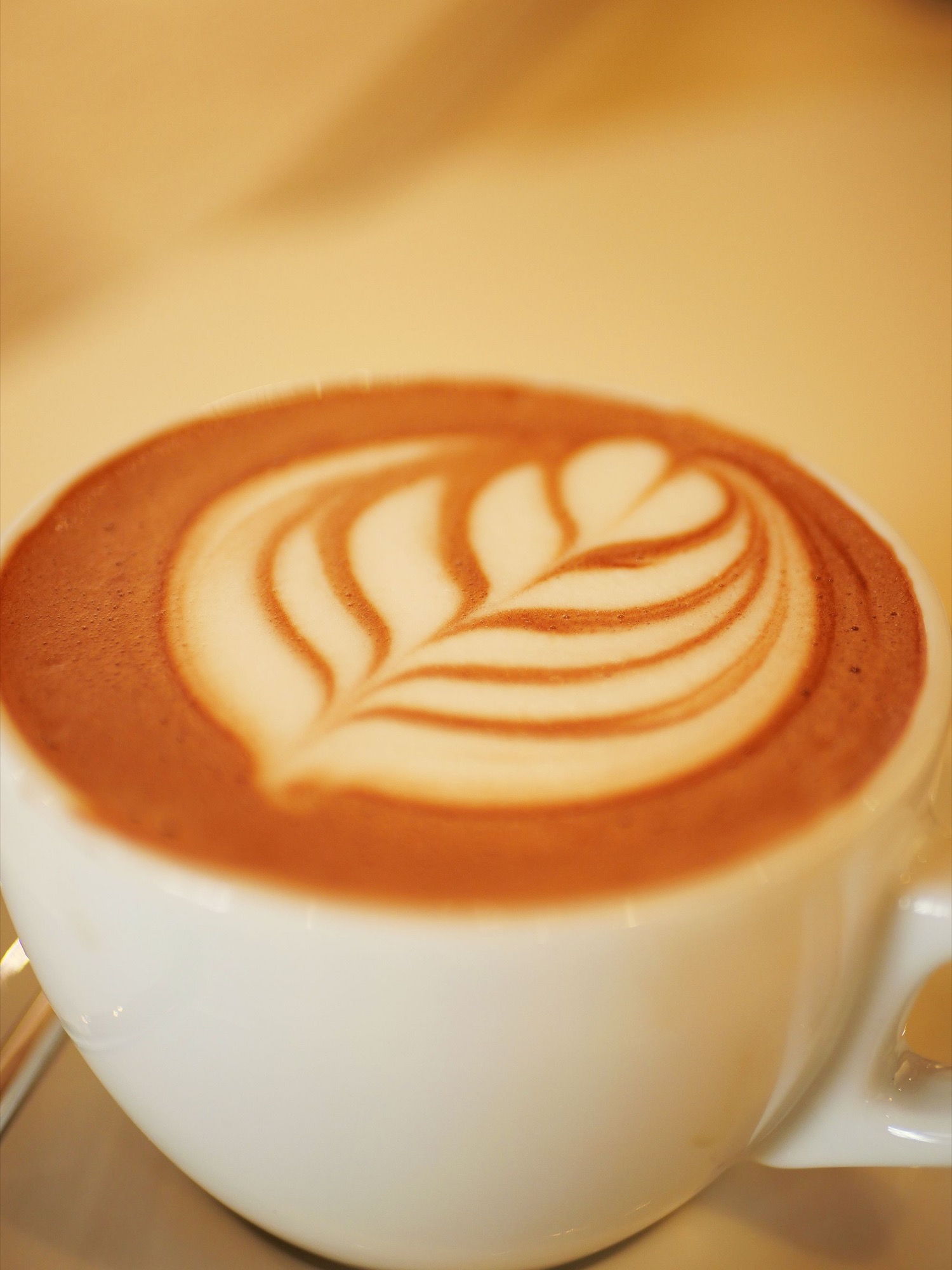 Close view of leaf-shaped latte art in a ceramic cup