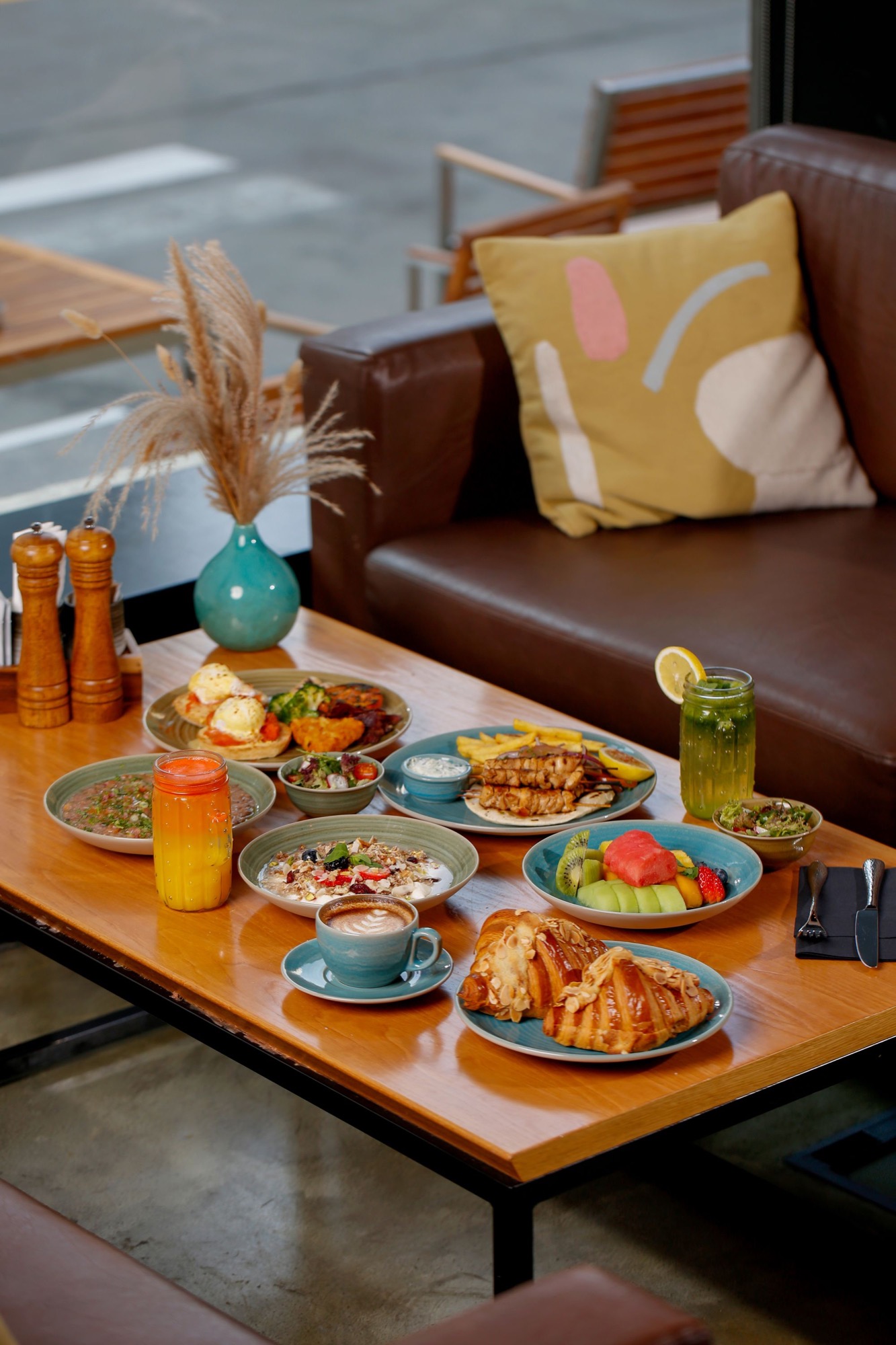 Colourful brunch dishes, coffee and juice arranged across a cafe table