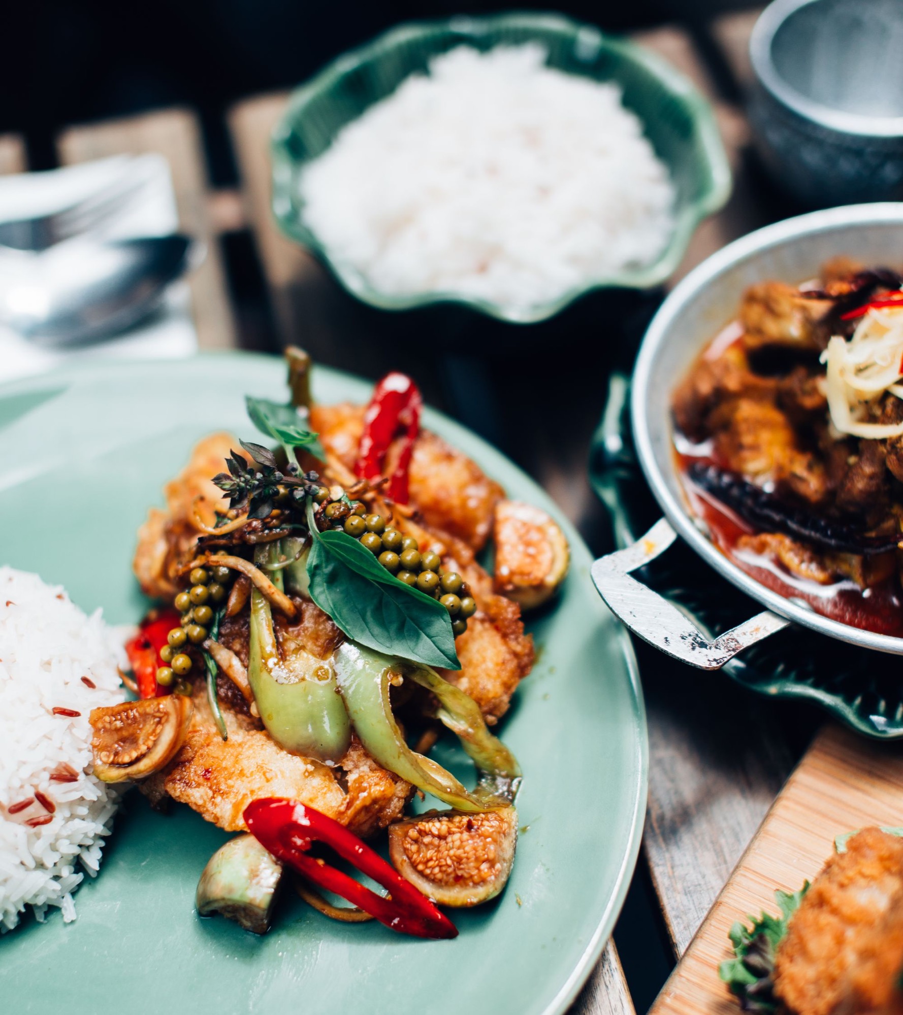 Thai dishes with herbs and chilli served at a restaurant table