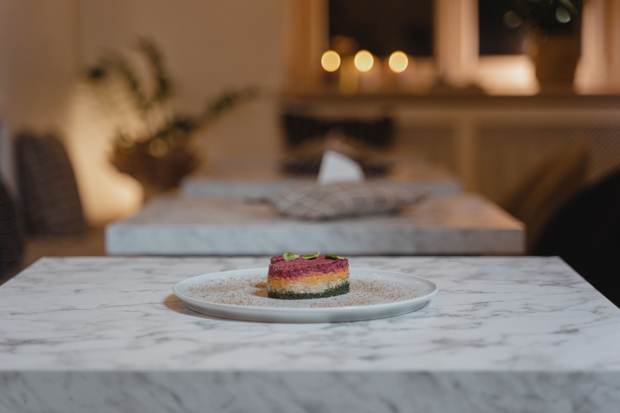 Small plated course served on marble in a softly lit dining room