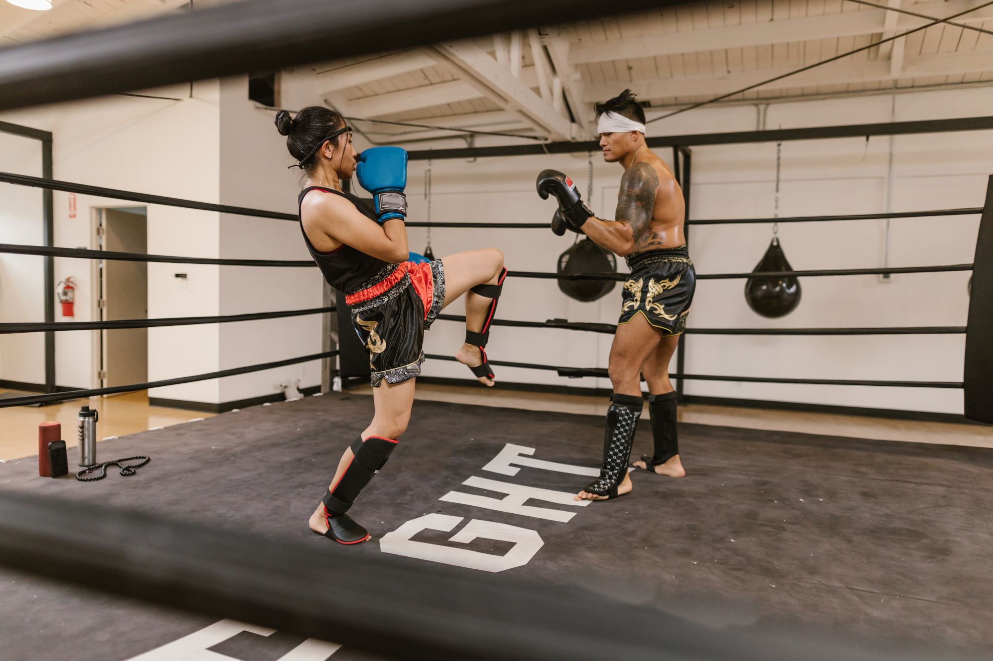 Two athletes practising Muay Thai combinations inside a boxing ring