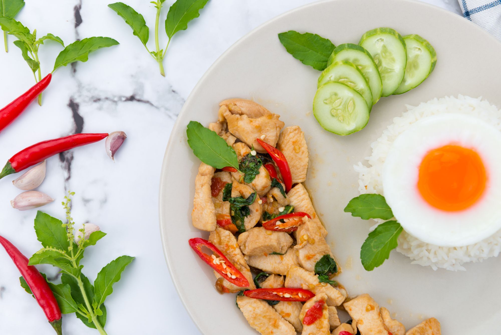 Spicy Thai basil stir-fry served with rice, egg, cucumber and chilli